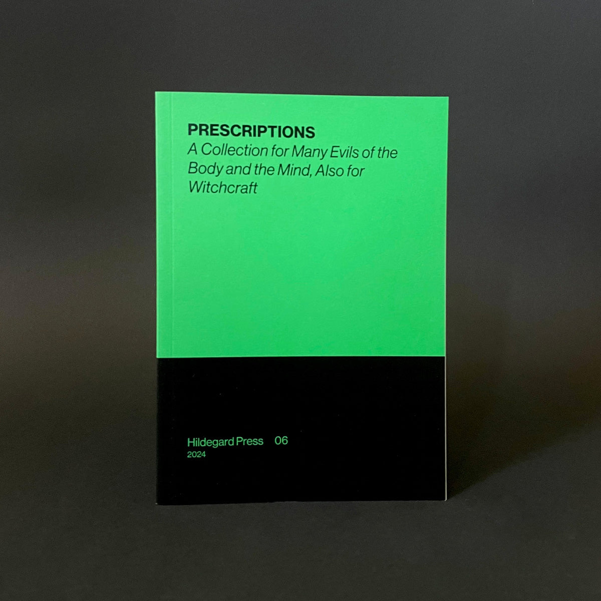 Book titled 'Prescriptions' with green and black cover on a dark background