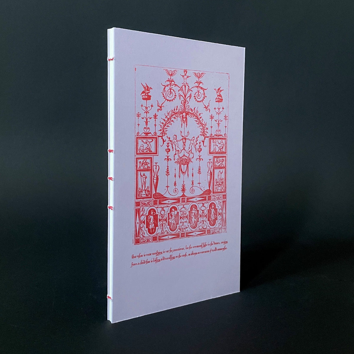 A portrait format notebook with a red riso ink print on the cover featuring coptic designs and a quote from Bulgakov’s The Master and Margarita.
