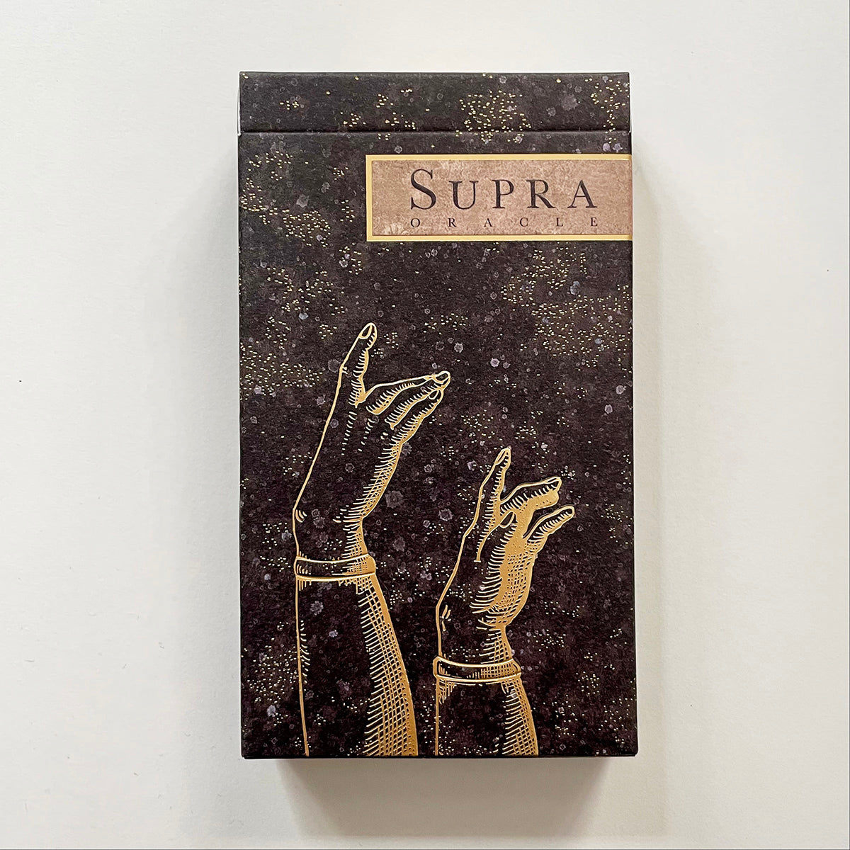 An oracle deck titled "Supra" with box displaying embossed gold hands against a light background.