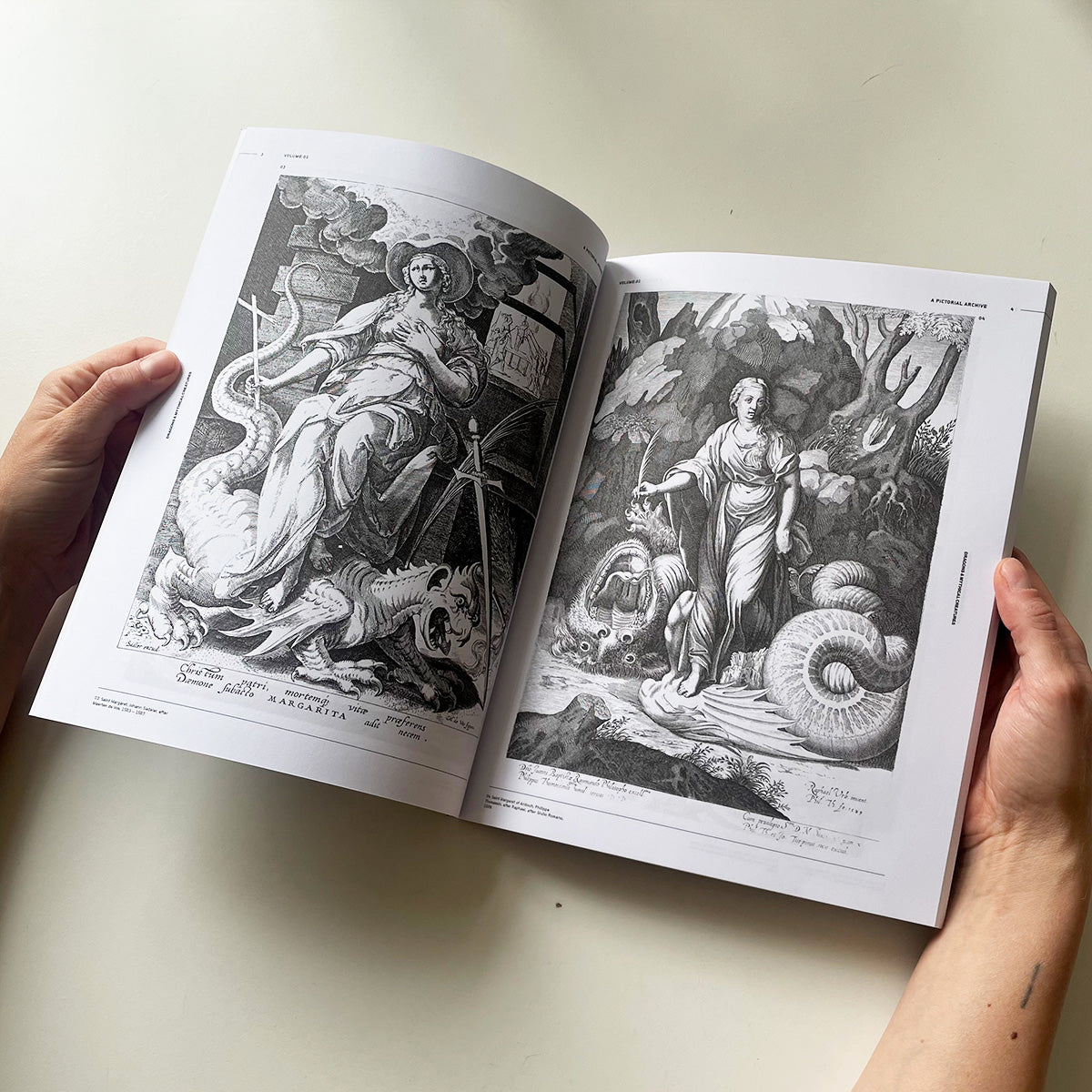 Open book with black and white illustrations of classical figures on a light background
