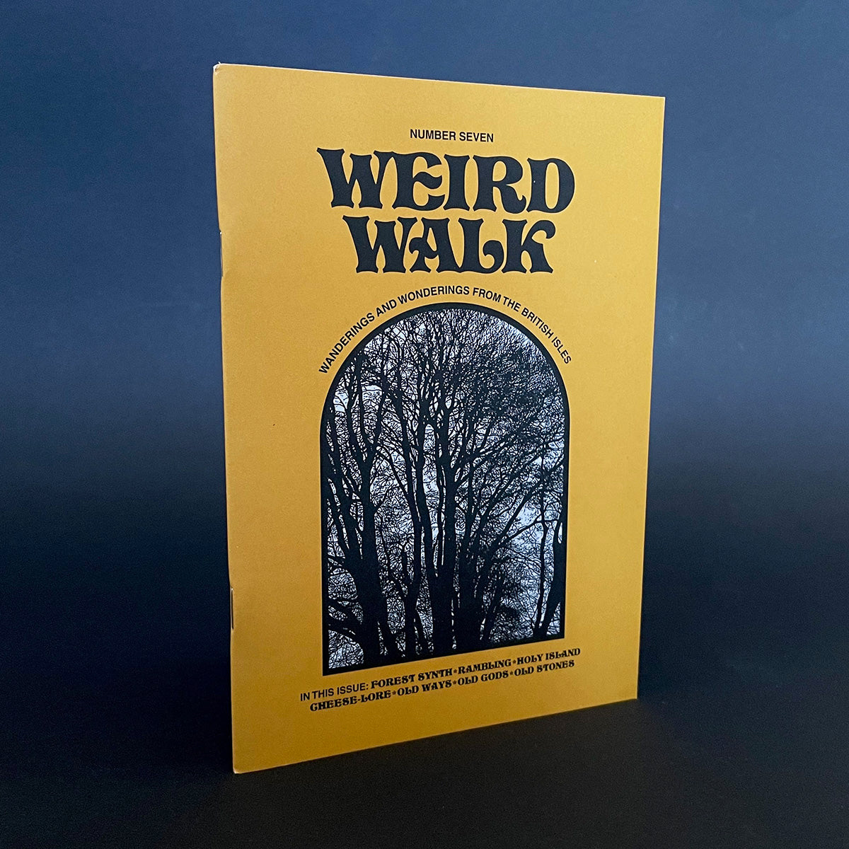 A cover image of 'Weird Walk Issue 7' magazine with a graphic of a forest on the cover against a dark background. 